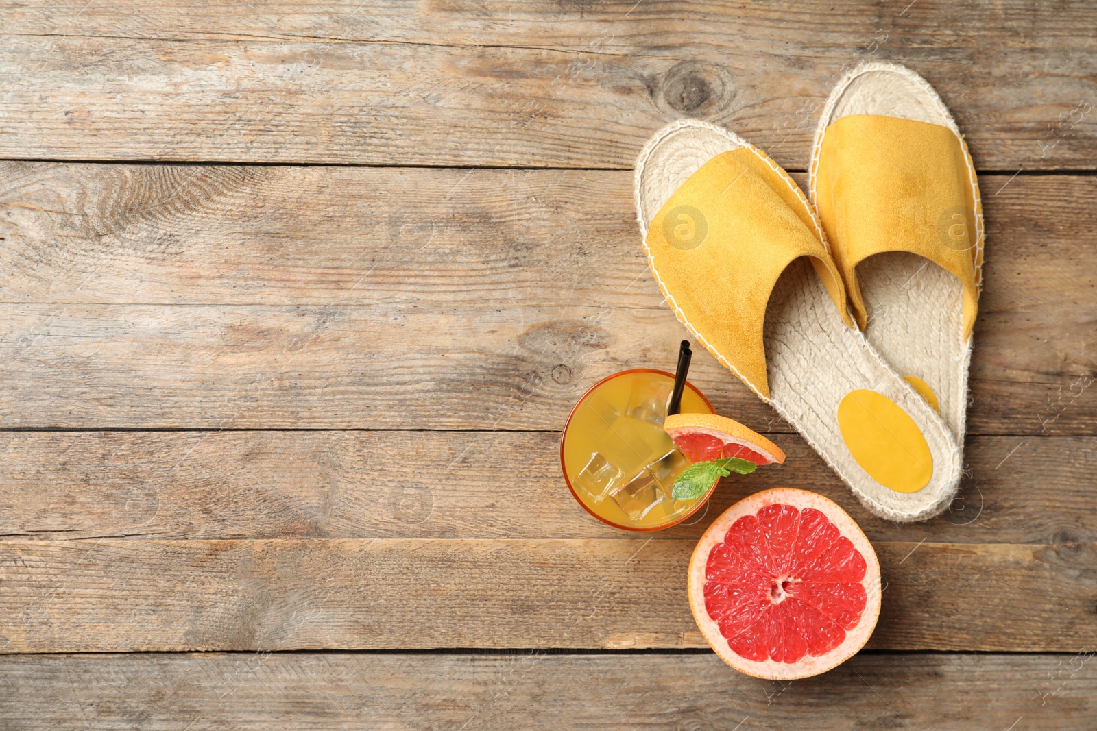 Photo of Slide shoes, cocktail, grapefruit and space for text on wooden background, flat lay. Beach objects