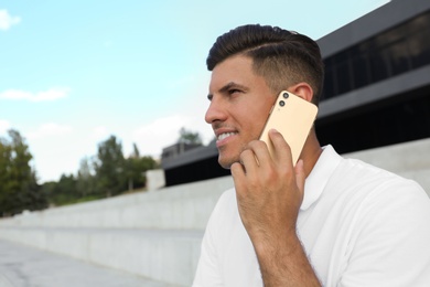 Man talking on modern mobile phone outdoors