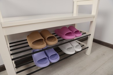 Photo of Storage bench with pairs of rubber slippers in room