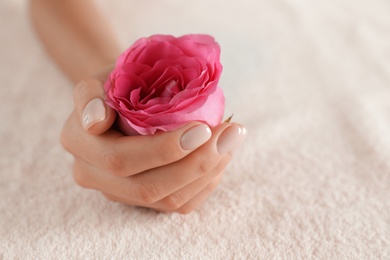 Closeup view of woman with smooth hand and flower on towel, space for text. Spa treatment