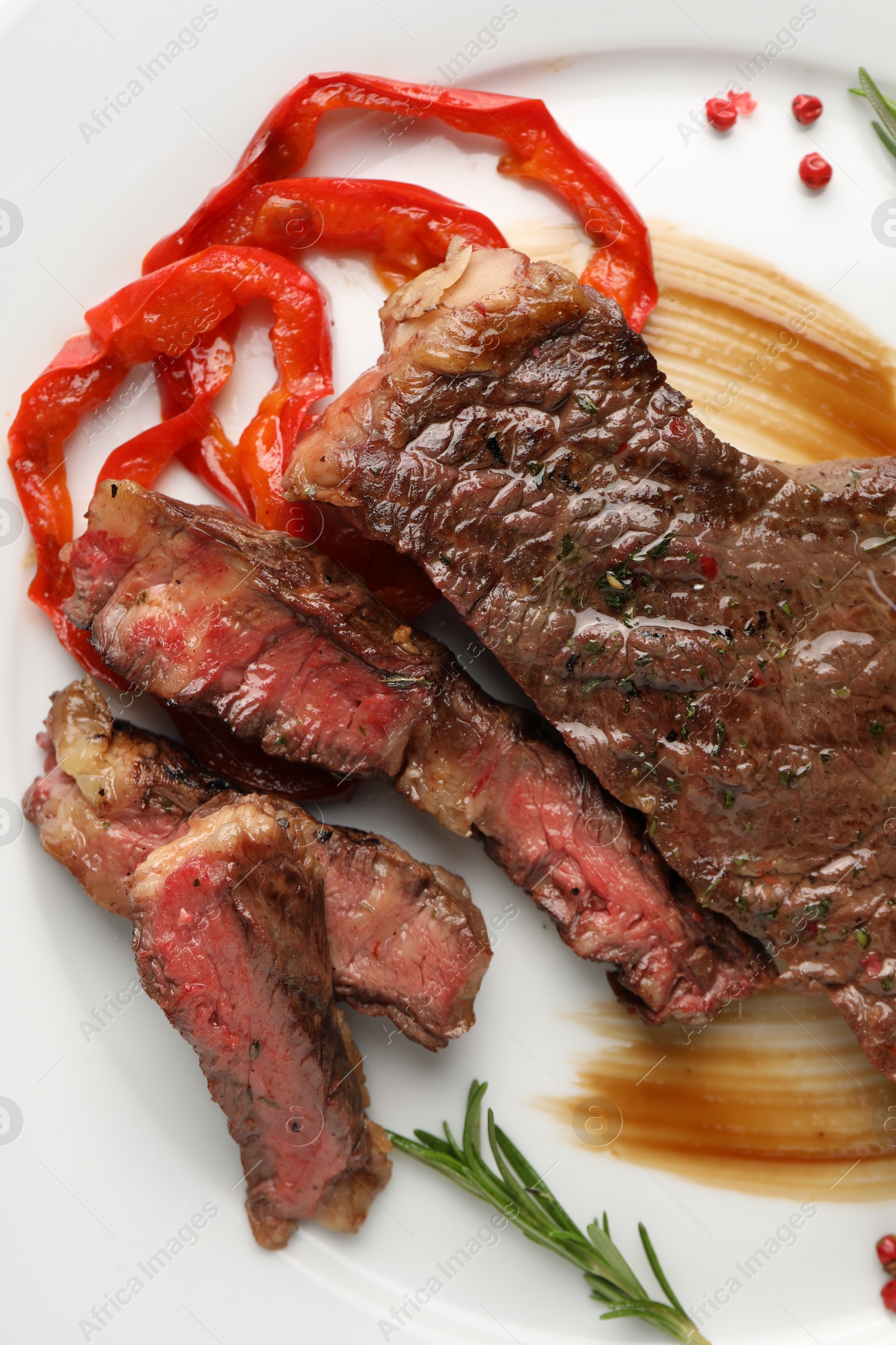 Photo of Delicious grilled beef steak with pepper and spices served on plate, top view