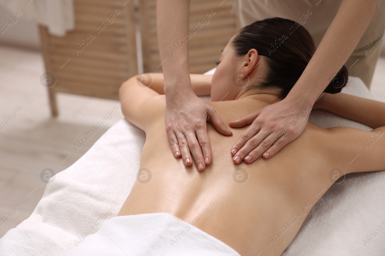 Photo of Woman receiving back massage on couch in spa salon