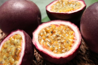 Cut and whole passion fruits (maracuyas) on wicker mat, closeup