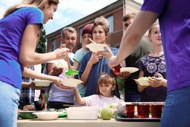 Photo of Volunteers serving food for poor people outdoors