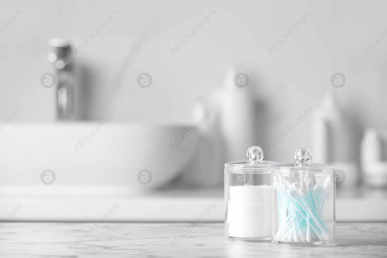 Photo of Plastic jars with cotton pads and swabs on white countertop in bathroom. Space for text