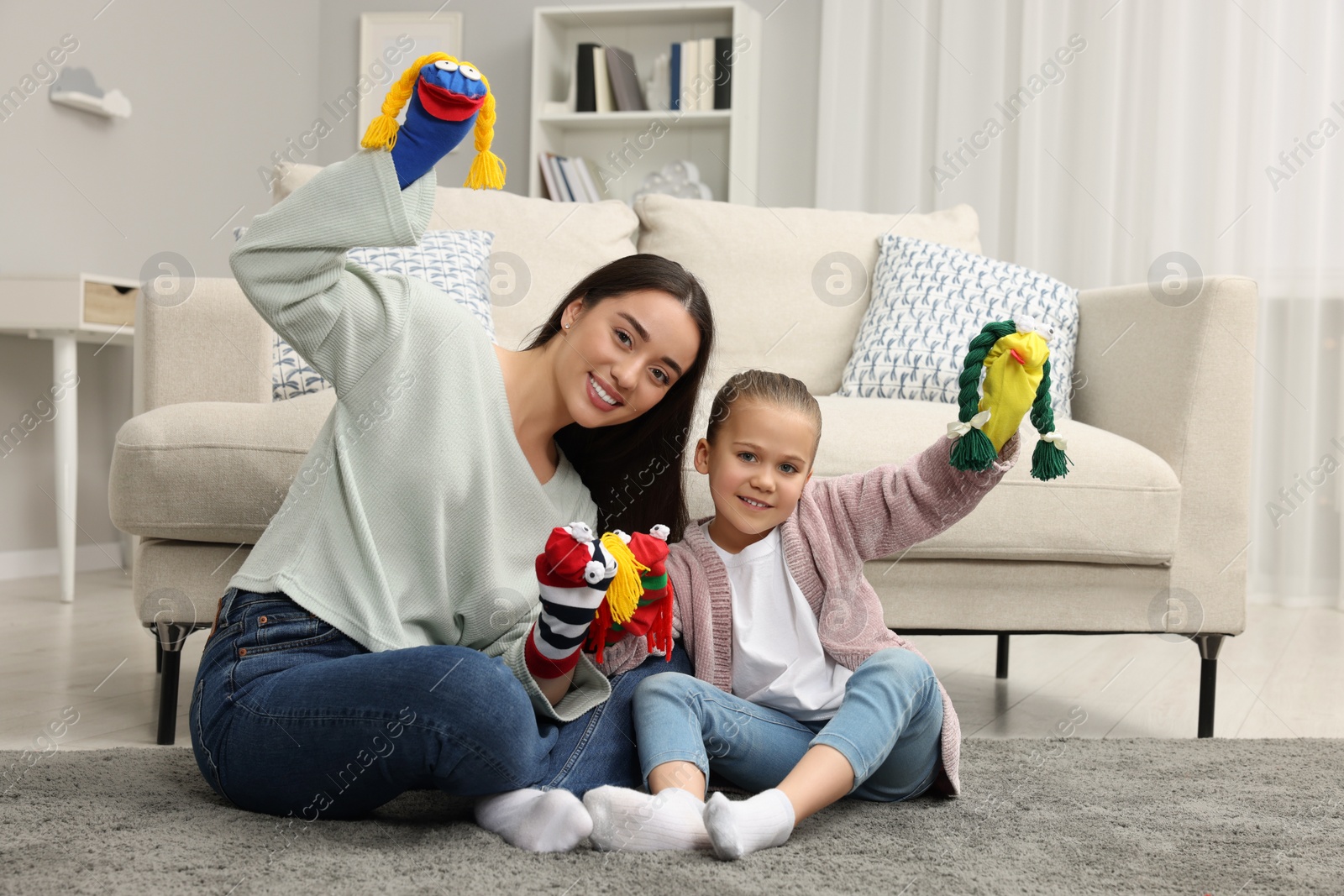 Photo of Happy mother and daughter playing with funny sock puppets together at home