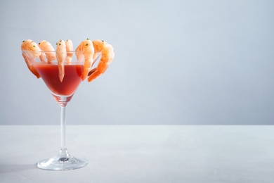 Photo of Glass with boiled shrimps and tomato sauce on table