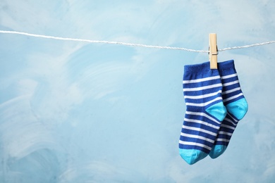 Photo of Pair of cute child socks on laundry line against color background. Space for text