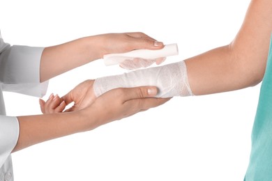 Doctor applying bandage onto patient's arm on white background, closeup