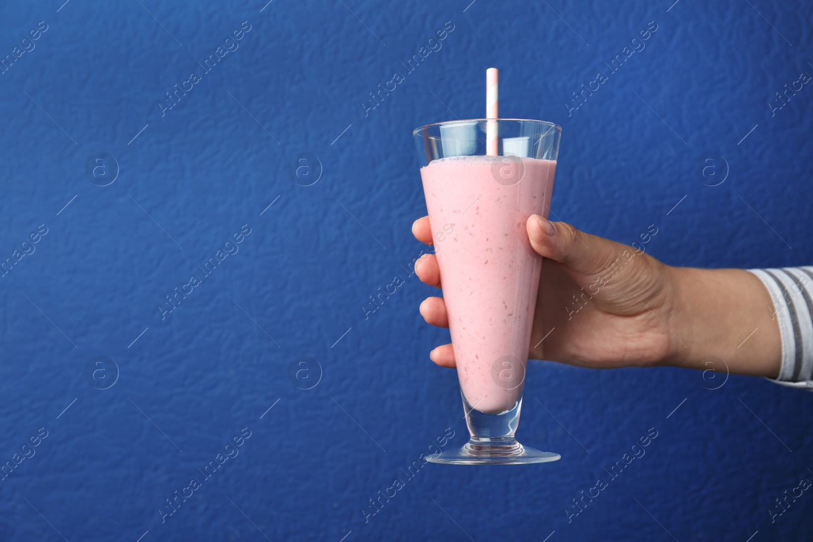 Image of Woman with glass of tasty smoothie on blue background, closeup. Space for text 