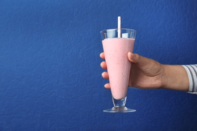 Woman with glass of tasty smoothie on blue background, closeup. Space for text 