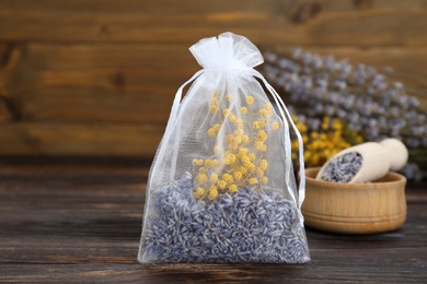 Scented sachet with dried flowers on wooden table, closeup