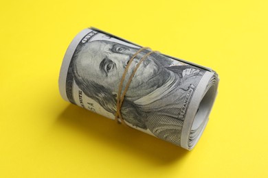 Photo of Rolled dollar banknotes on yellow background, closeup. American national currency
