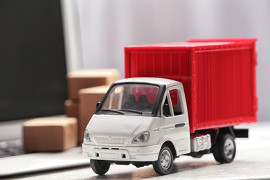 Photo of Toy truck near laptop on table. Logistics and wholesale concept