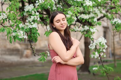 Beautiful woman near blossoming tree on spring day