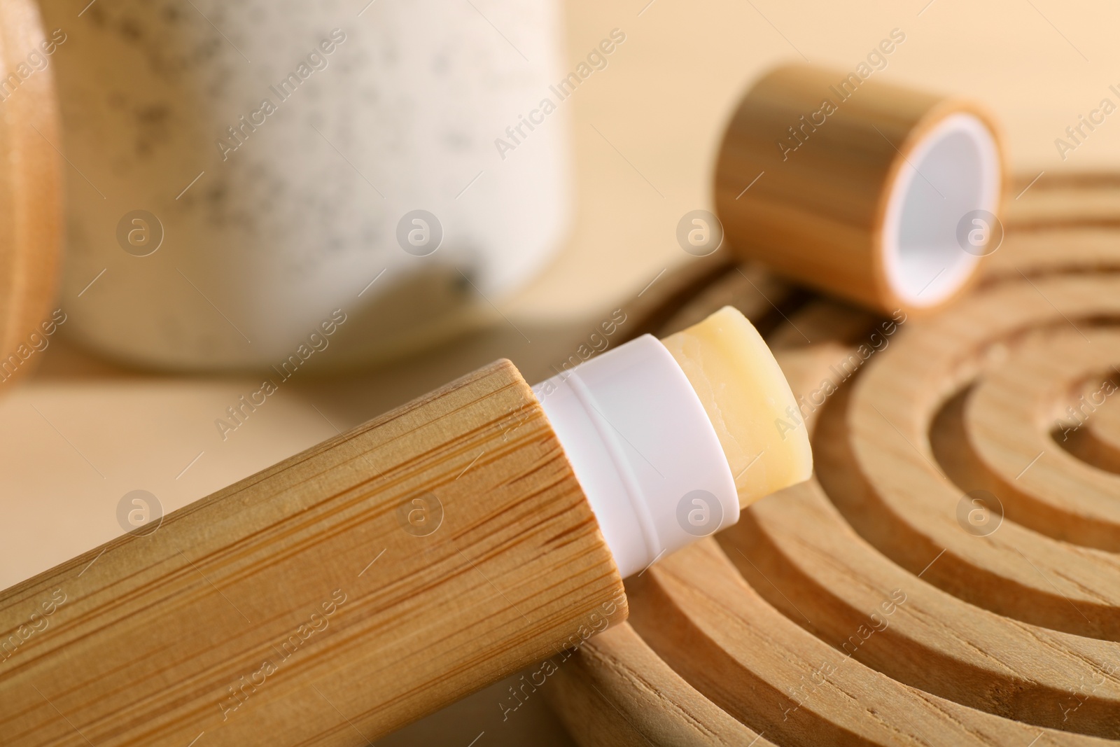 Photo of Lip balm on wooden coaster against blurred background, closeup