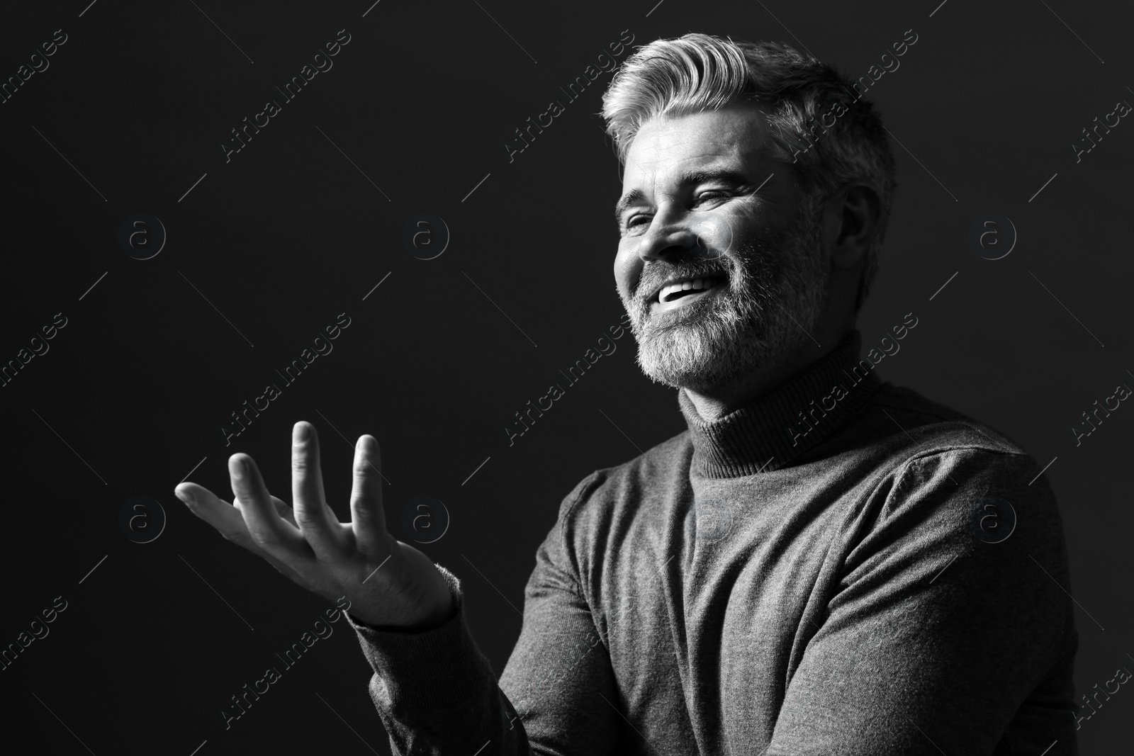 Photo of Portrait of smiling man on dark background. Black and white effect