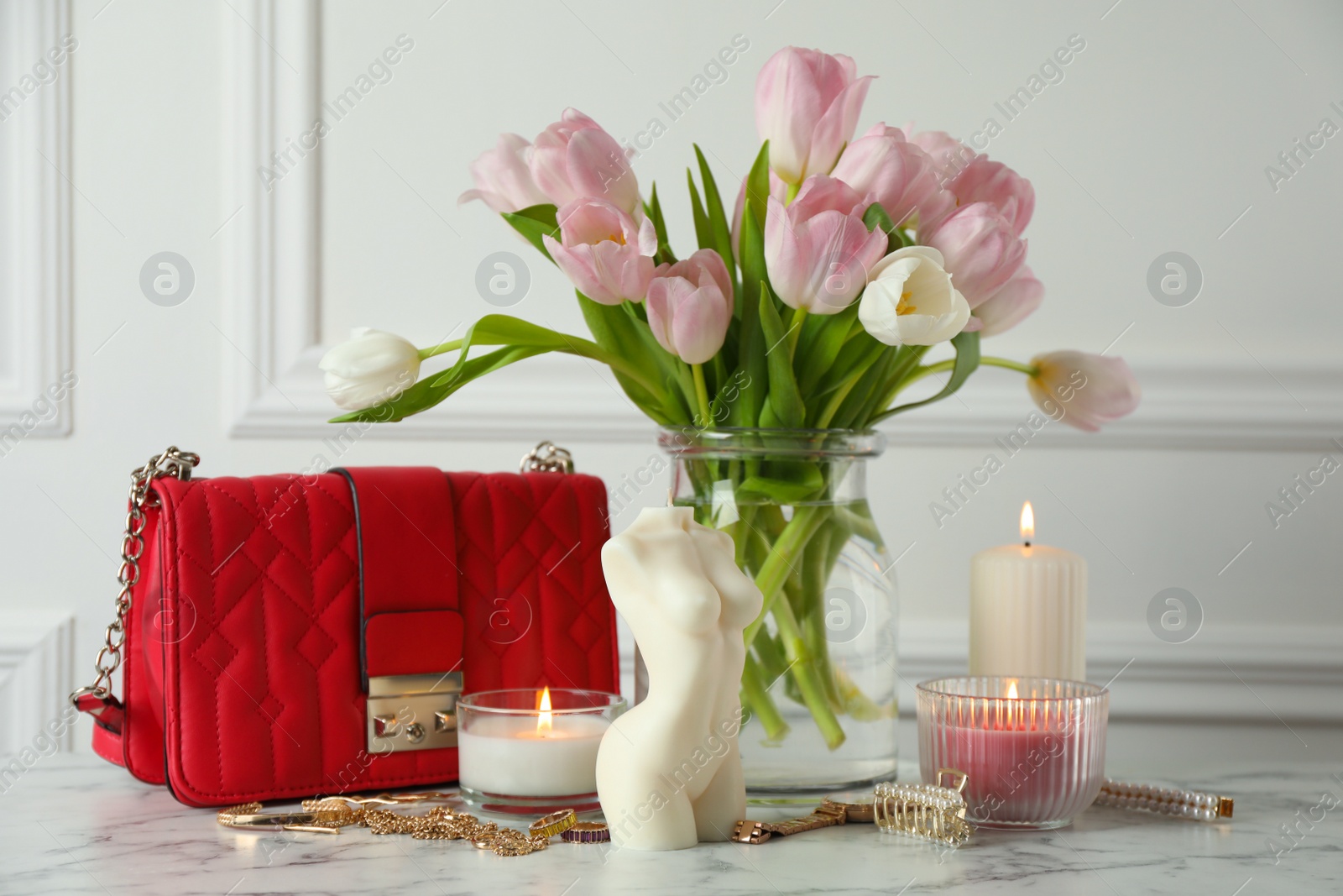 Photo of Beautiful female body shaped candle and tulips on white marble table. Stylish decor