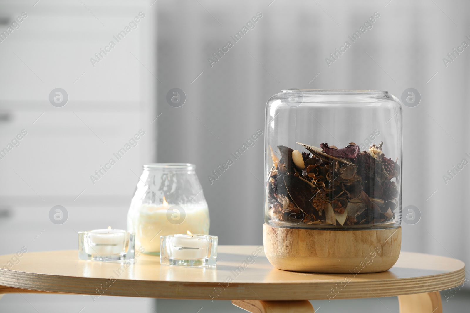 Photo of Decorative jar with aromatic potpourri and candles on wooden table in room, space for text