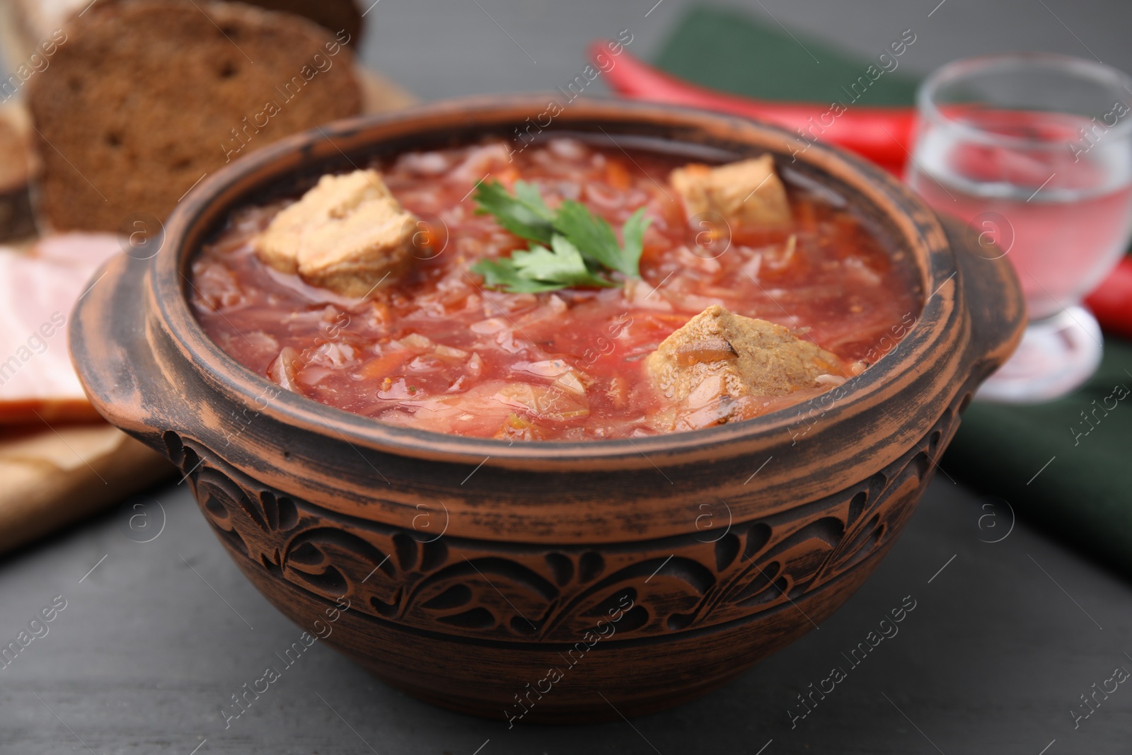 Photo of Tasty borscht in bowl on grey wooden table, closeup
