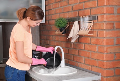 Woman washing modern multi cooker in kitchen sink
