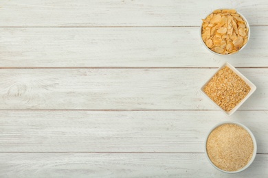 Bowls with different dried garlic on wooden table, top view