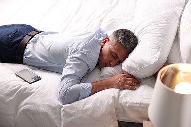 Businessman in office clothes sleeping on bed indoors