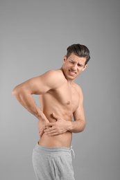 Photo of Young man suffering from flank pain on grey background