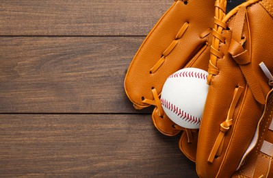 Photo of Leather baseball glove with ball on wooden table, top view. Space for text