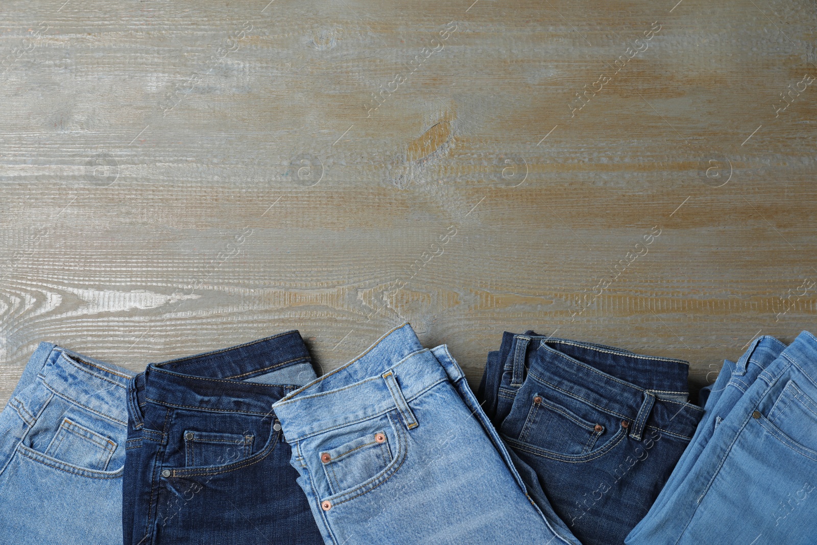 Photo of New stylish jeans on wooden background, flat lay. Space for text