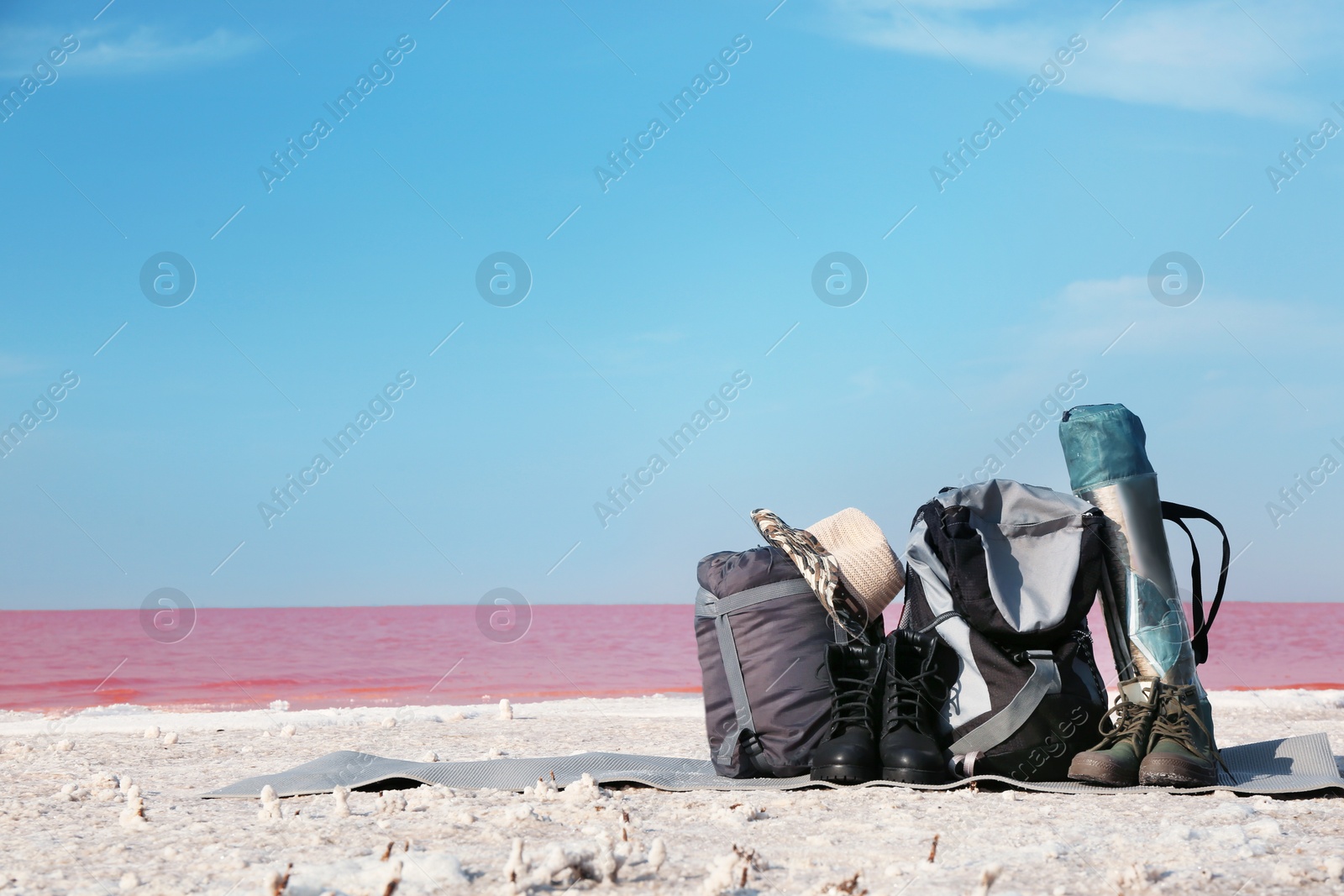 Photo of Set of camping equipment with sleeping bag on coast of pink lake