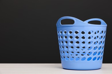 Photo of Empty plastic laundry basket near dark grey wall. Space for text