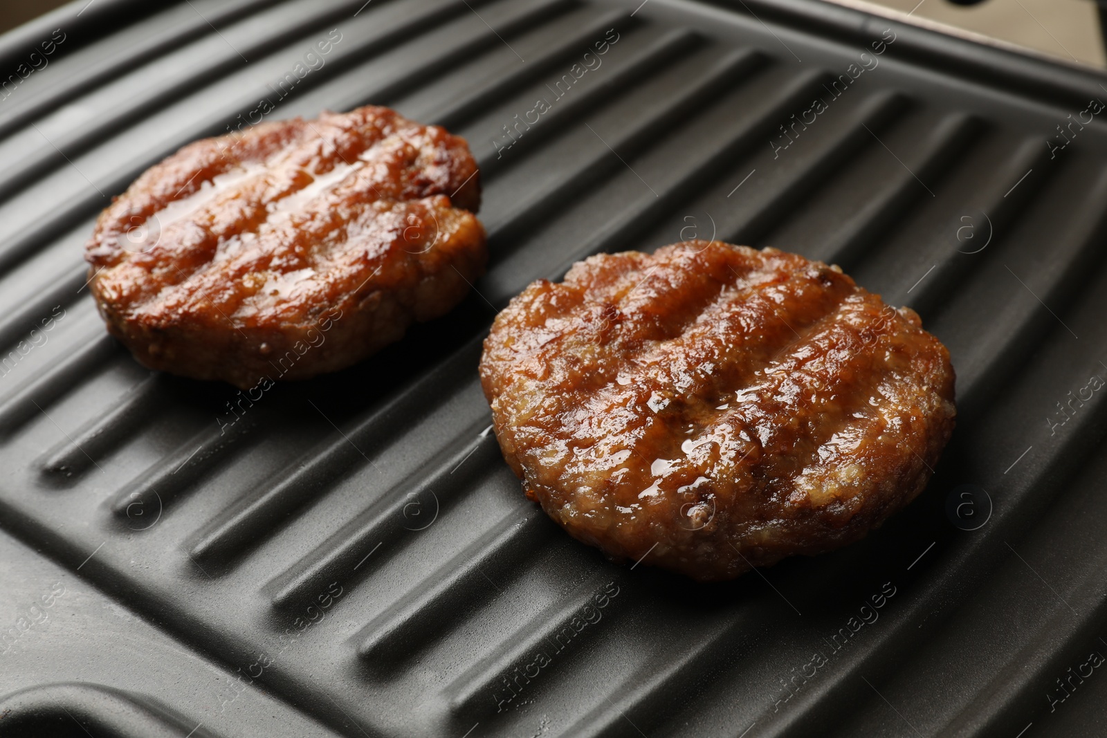 Photo of Delicious hamburger patties on electric grill, closeup