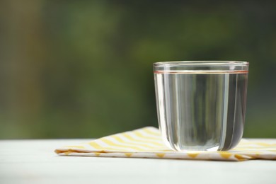 Photo of Glass of pure water on white table, space for text