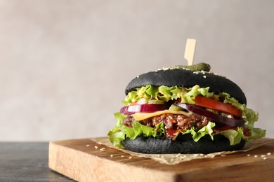 Photo of Board with black burger on table, space for text