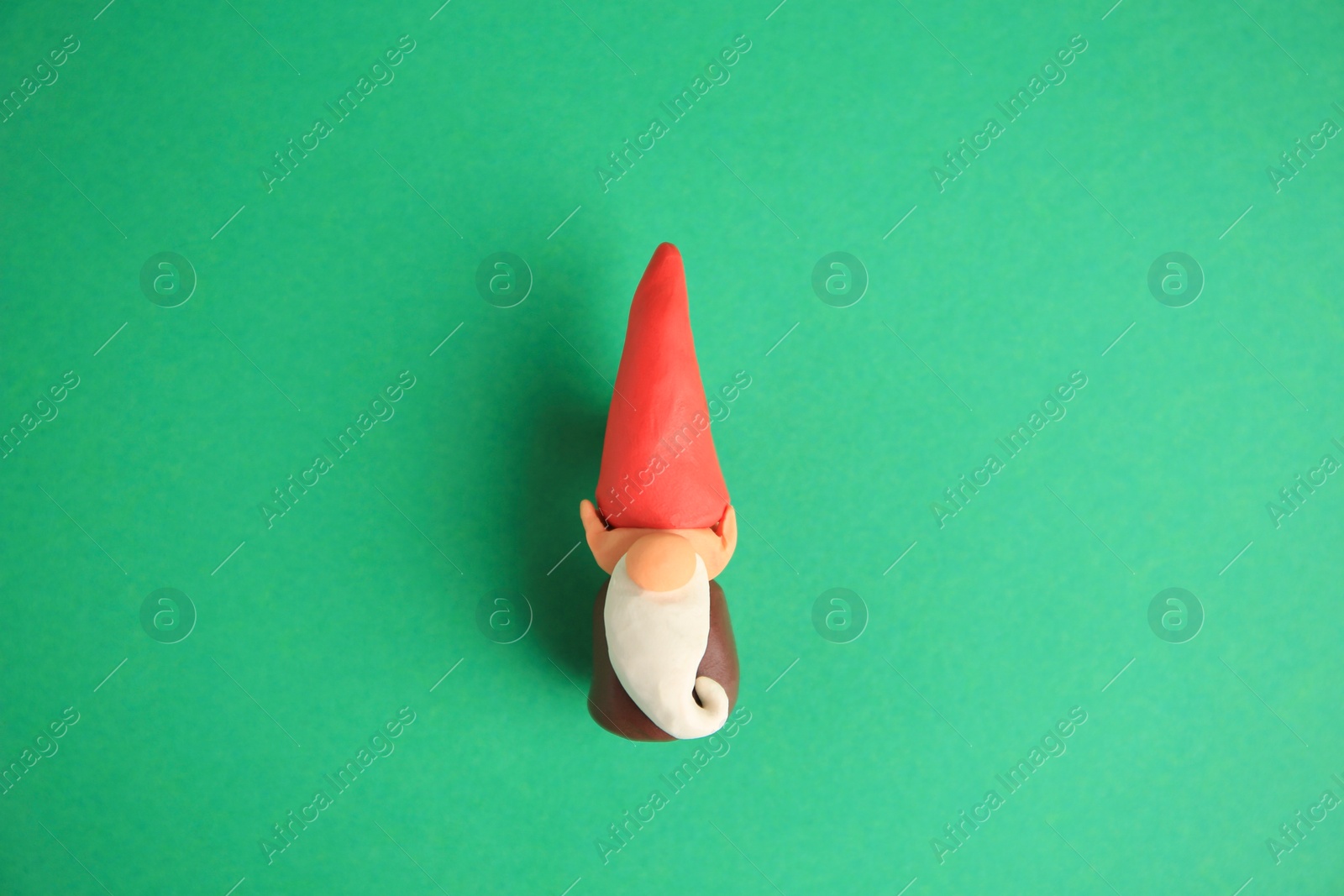 Photo of Dwarf made from plasticine on green background, top view. Children's handmade ideas