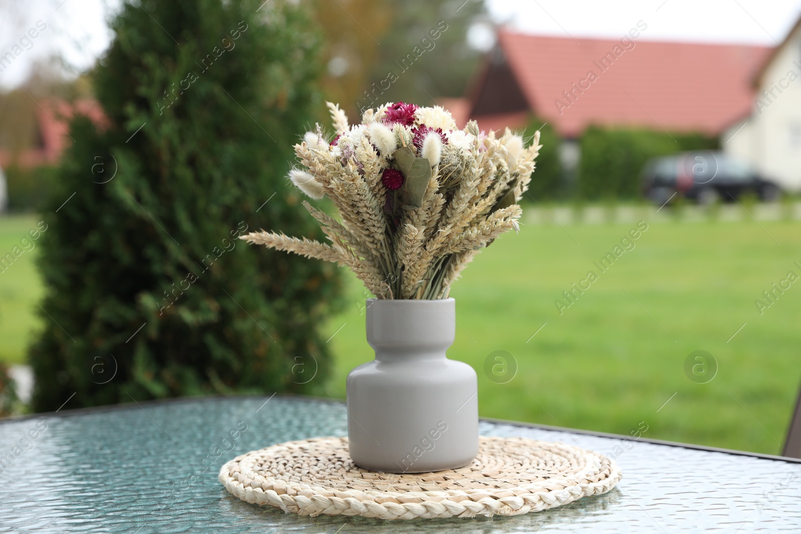 Photo of Beautiful bouquet of dry flowers in vase on glass table outdoors