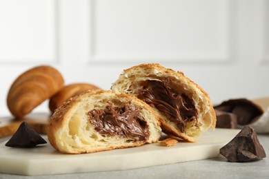 Photo of Tasty croissant with chocolate on light grey table