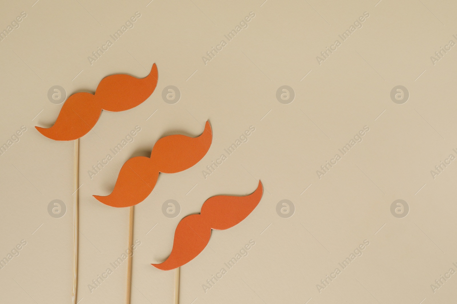 Photo of Fake paper mustaches party props on beige background, flat lay. Space for text