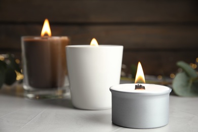 Burning scented candles on light grey table