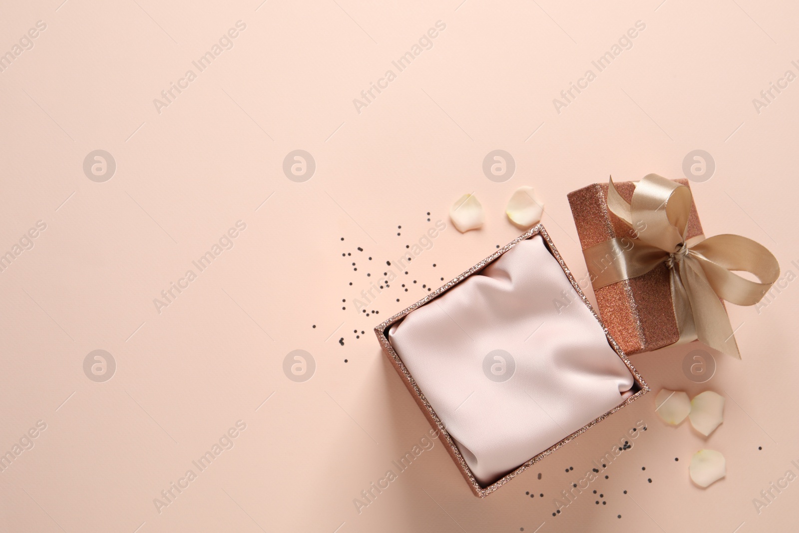 Photo of Open gift box, confetti and rose petals on pink background, flat lay. Space for text