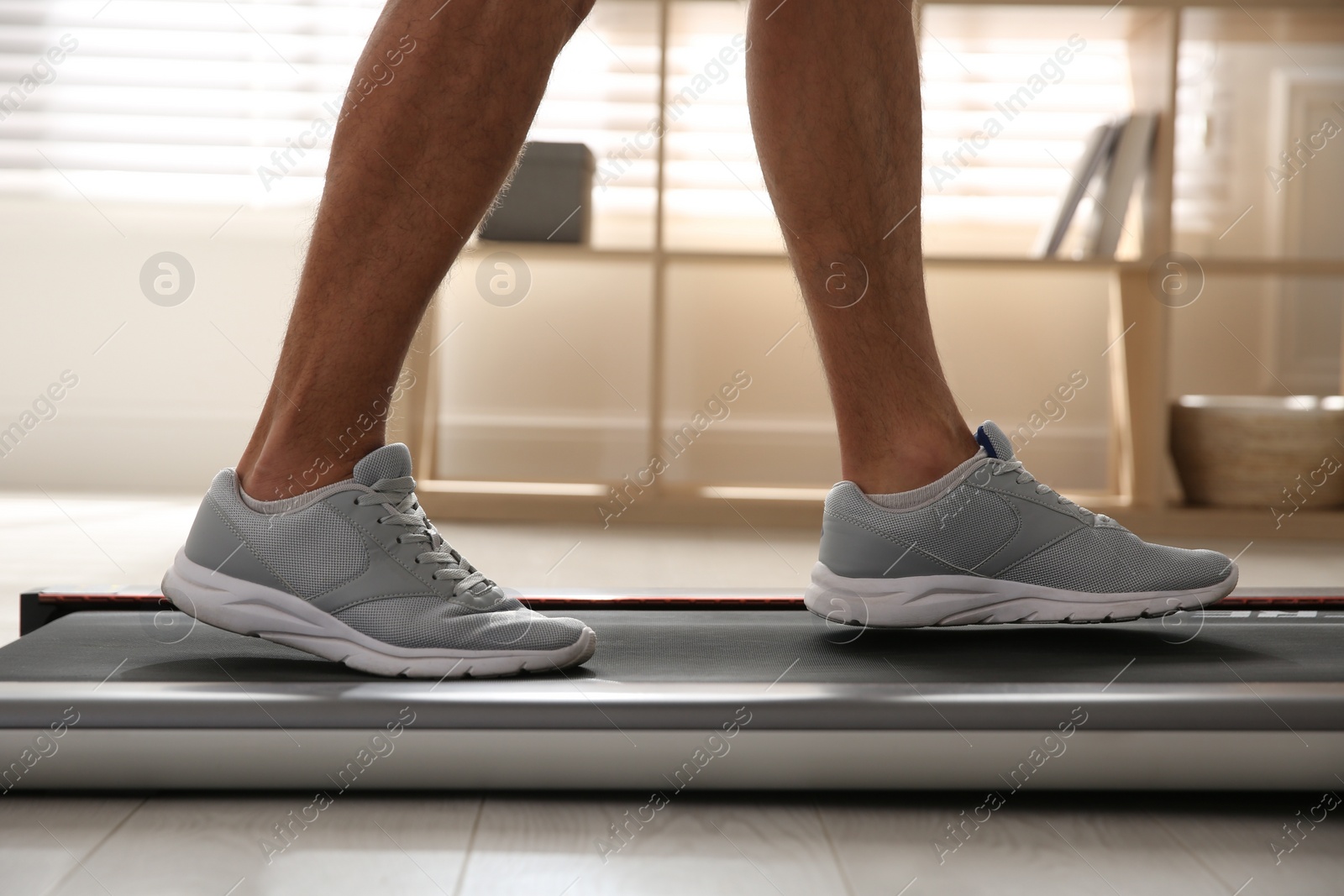 Photo of Sporty man training on walking treadmill at home, closeup
