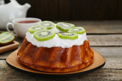 Homemade yogurt cake with kiwi and cream on wooden table