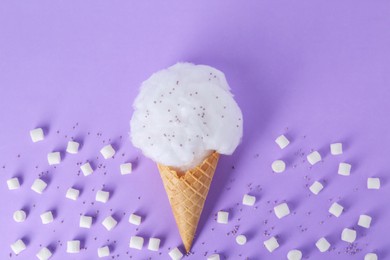 Sweet cotton candy in waffle cone and marshmallows on purple background, flat lay