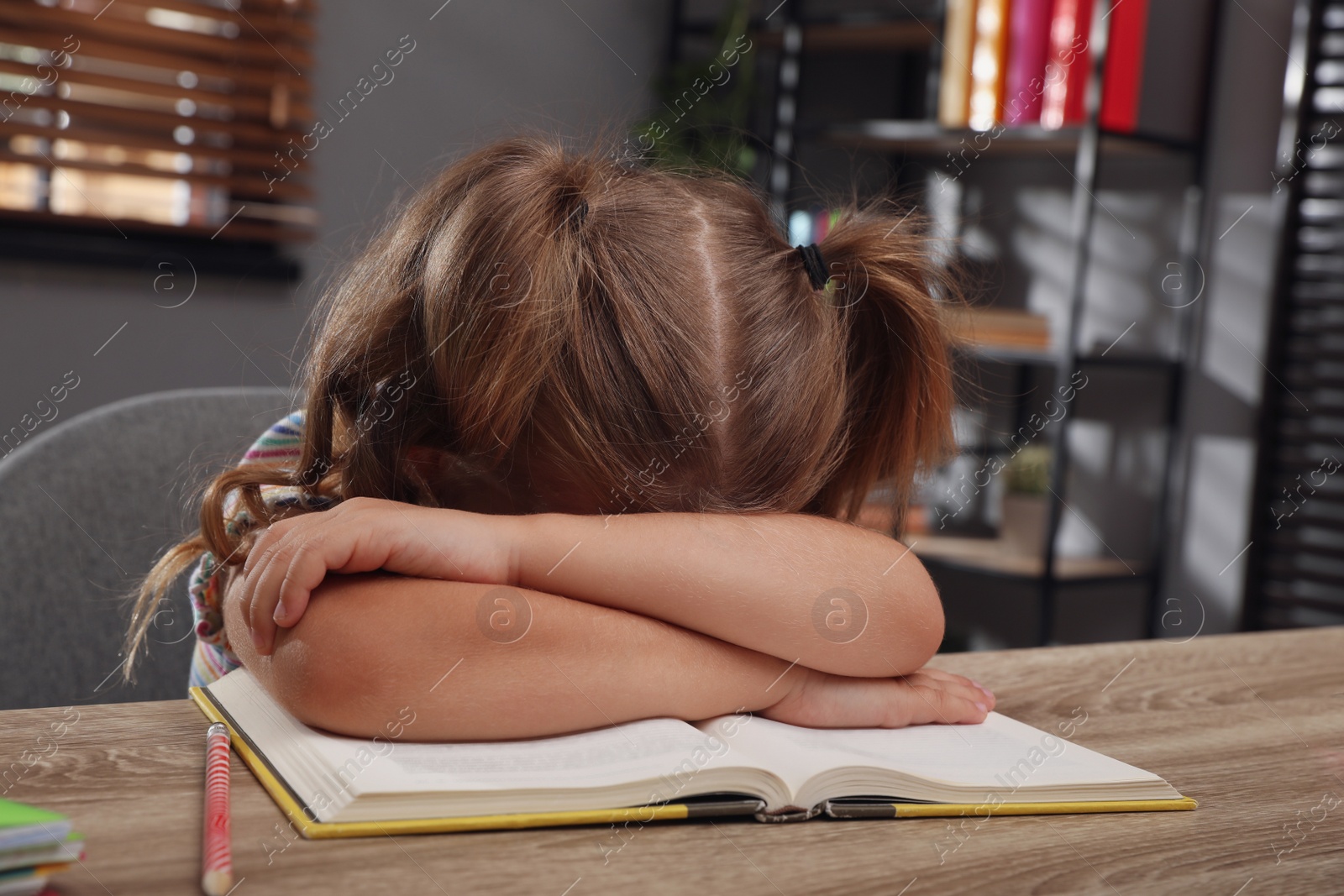 Photo of Tired little girl at table. Doing homework