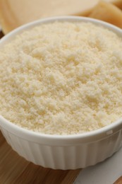 Photo of Bowl with grated parmesan cheese on white table, closeup