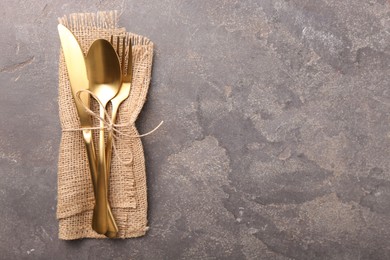 Photo of Set of stylish cutlery and napkin on grey textured table, top view. Space for text