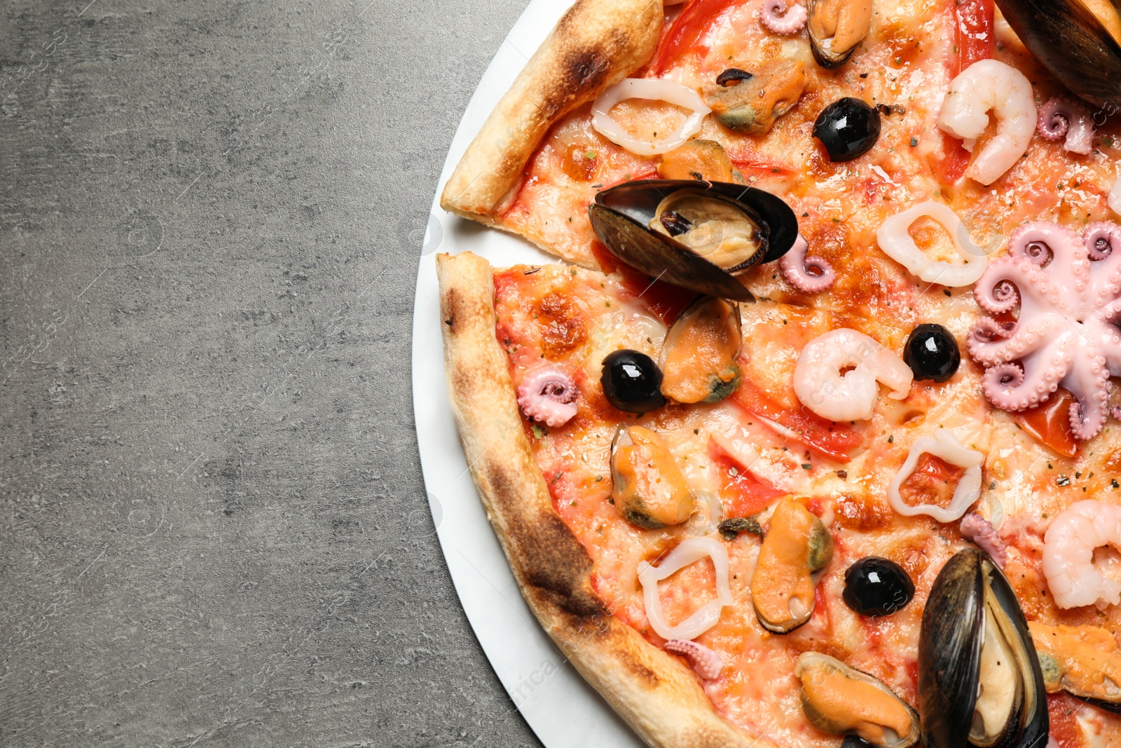 Photo of Delicious seafood pizza on grey table, top view