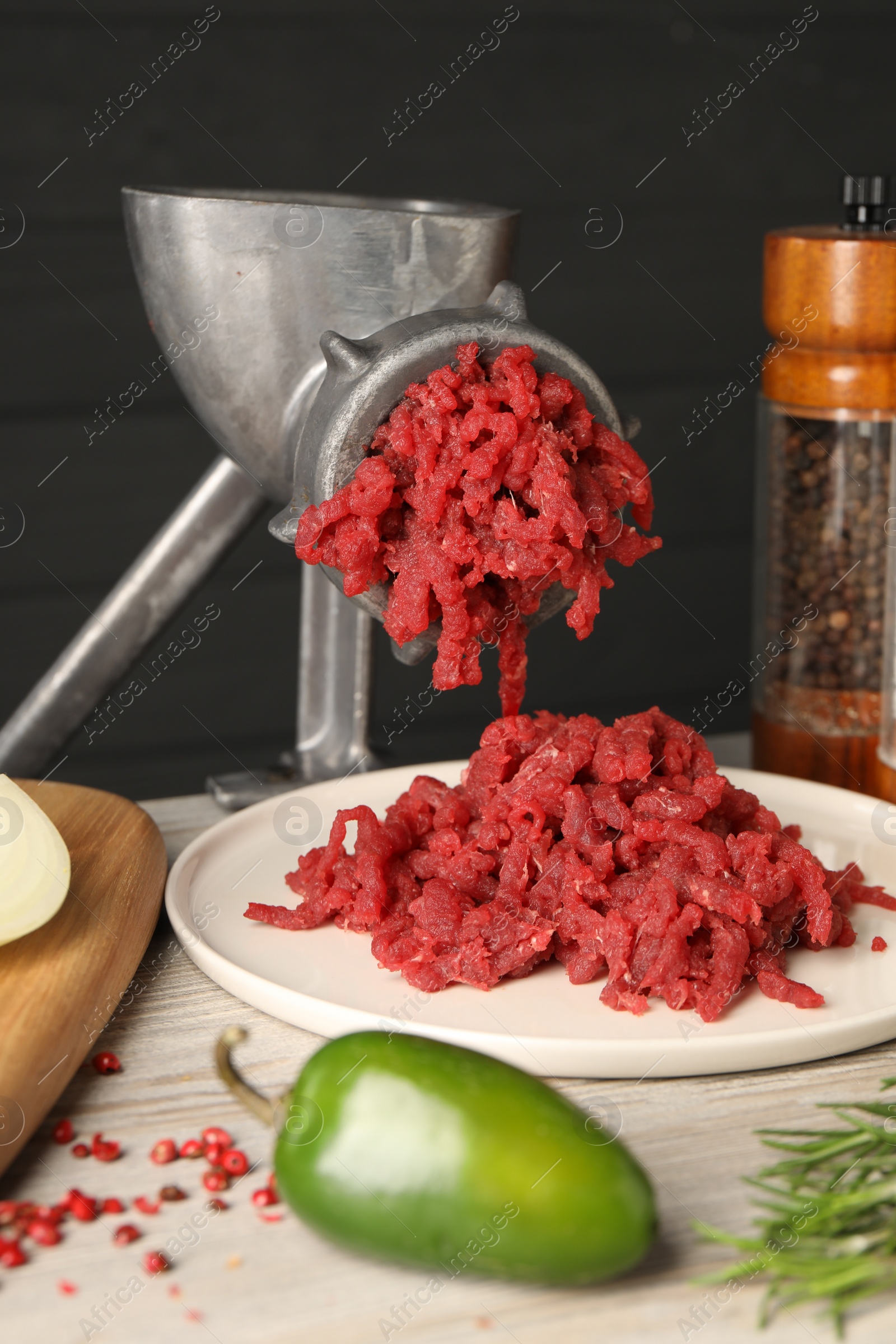 Photo of Metal meat grinder with minced beef on light wooden table