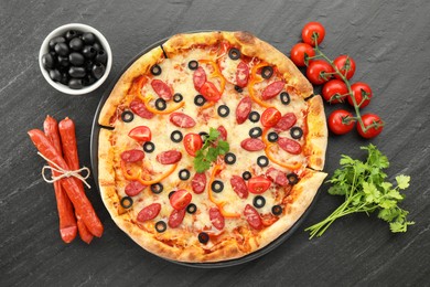 Photo of Tasty pizza with dry smoked sausages, olives, tomatoes, pepper and parsley on grey table, top view